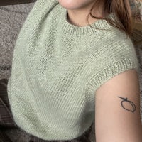 a woman wearing a green sweater with a tattoo