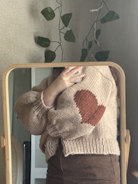 a woman is standing in front of a mirror wearing a sweater