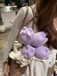 a woman is holding a bunch of crocheted tulips