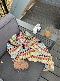 a crocheted blanket and a pair of shoes on a deck