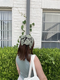 a woman wearing a white hat and carrying a bag