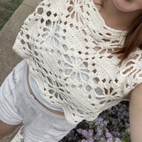a woman wearing a crocheted top and white shorts