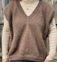 a woman wearing a brown sweater and striped shirt